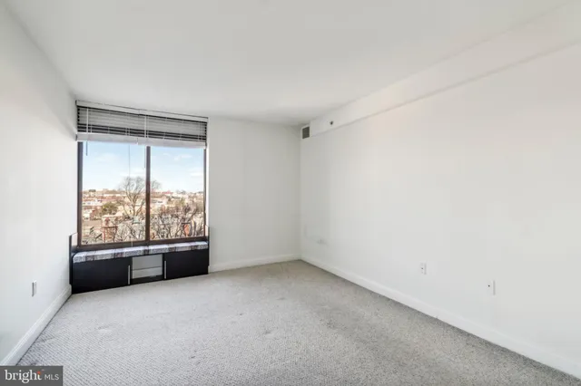 an empty room with a fireplace and large windows