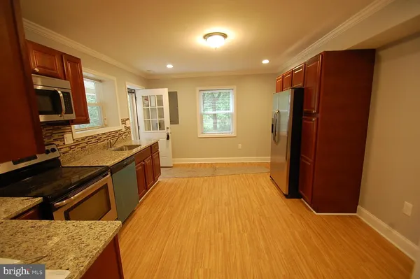 a kitchen with stainless steel appliances granite countertop a stove a sink dishwasher a refrigerator and a oven with wooden floor