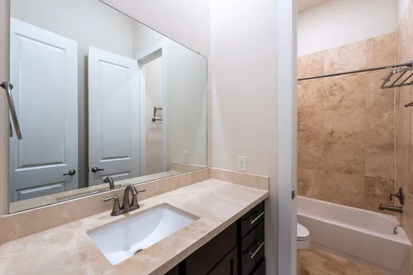 a bathroom with a granite countertop sink mirror and a bathtub