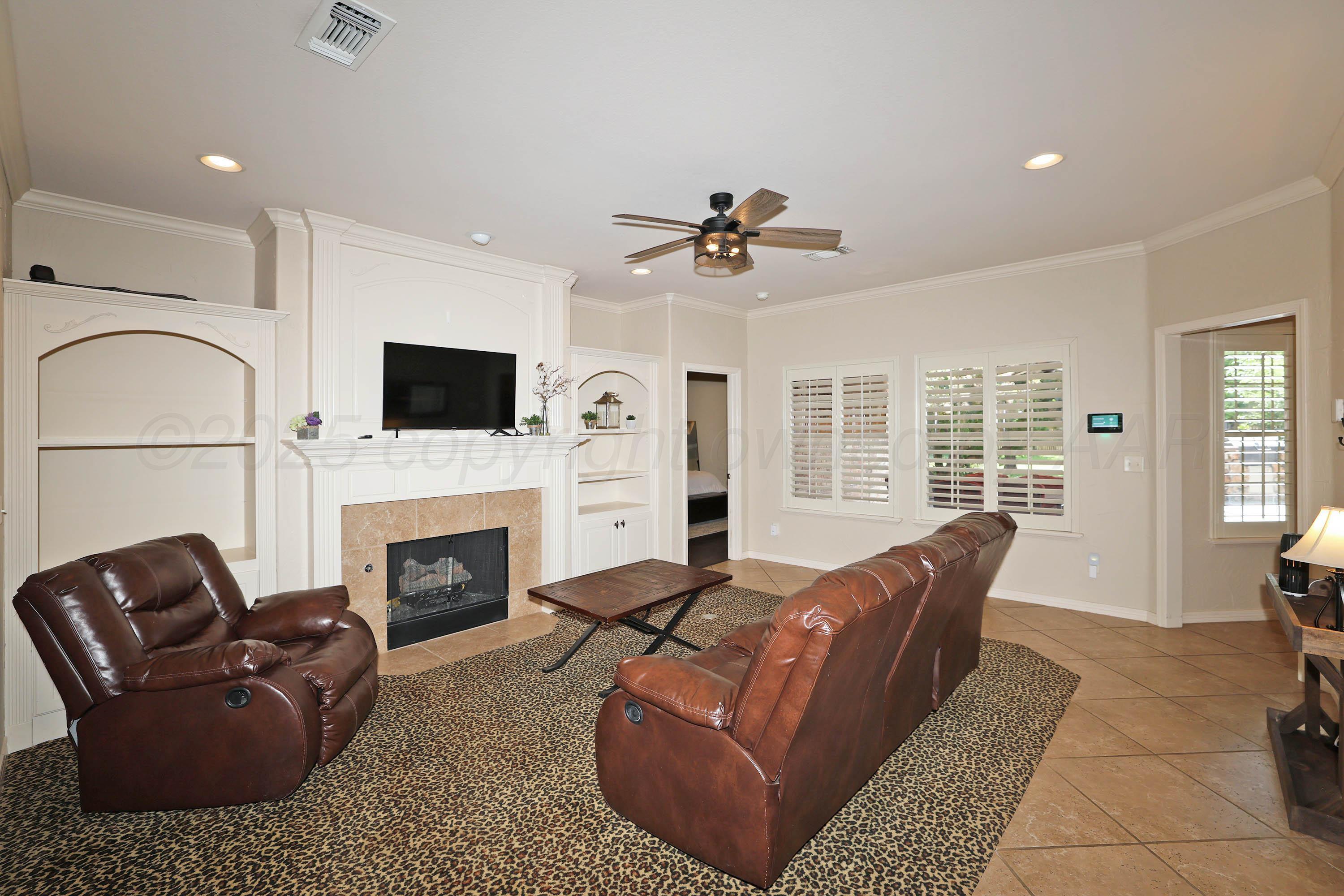 9220 Greyhawk Road Amarillo, TX 79119 - Photo 13 of 50 a living room with furniture a fireplace and a flat screen tv