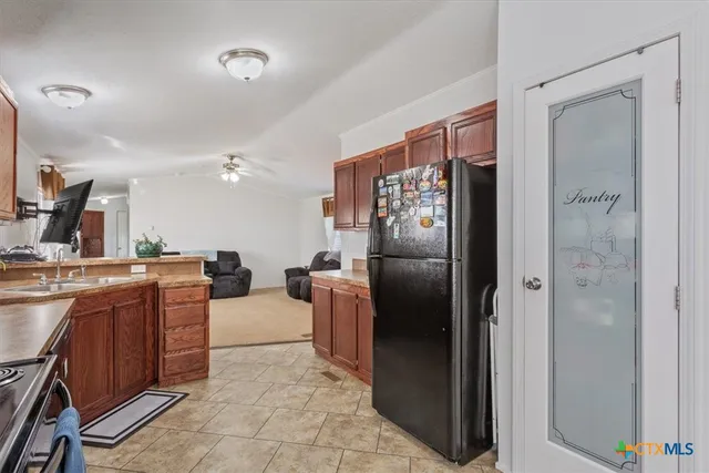 a living room with stainless steel appliances furniture a refrigerator and a sink