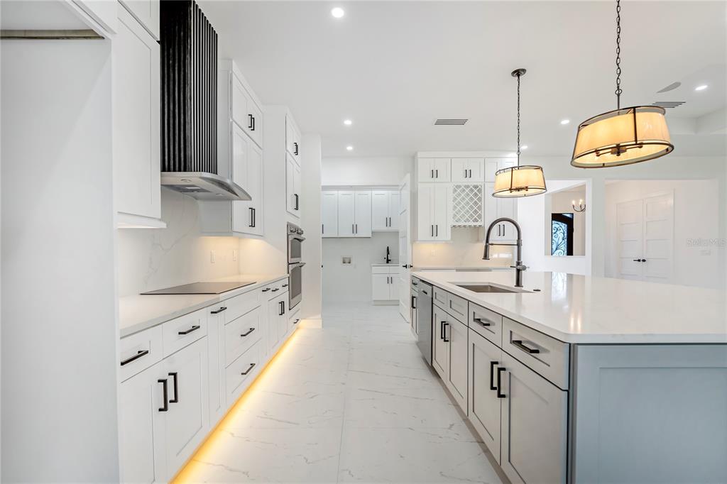 14080 Sydney Road Dover, FL 33527 - Photo 16 of 54 a large kitchen with kitchen island a stove a sink a center island and wooden floor