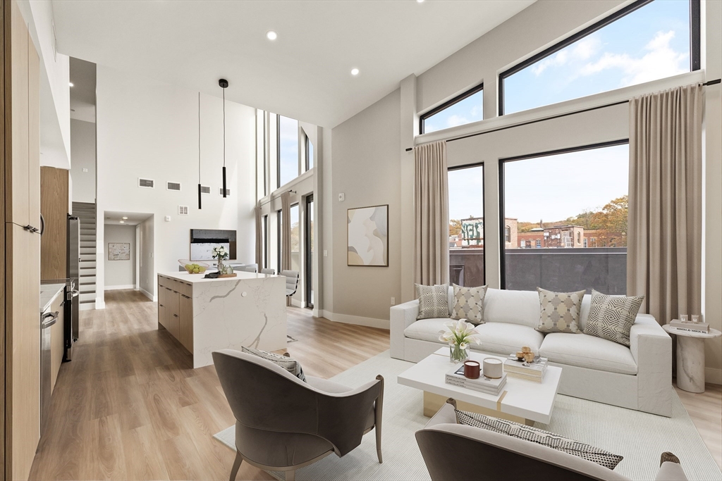 a living room with furniture large windows and wooden floor
