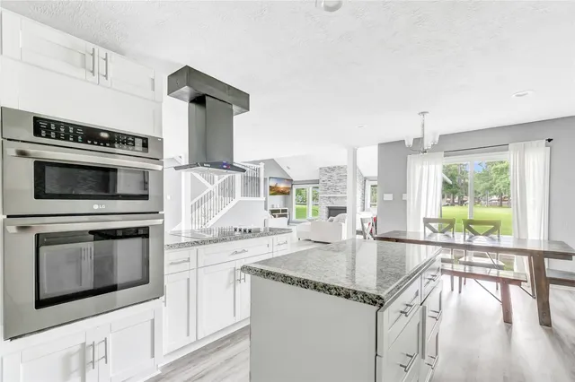 a kitchen with granite countertop a stove and white cabinets with wooden floor