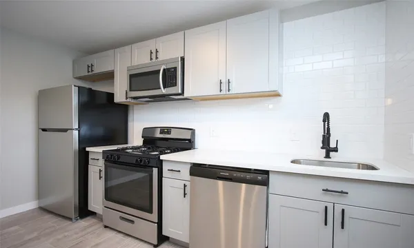 a kitchen with stainless steel appliances granite countertop white cabinets a microwave a sink and a refrigerator