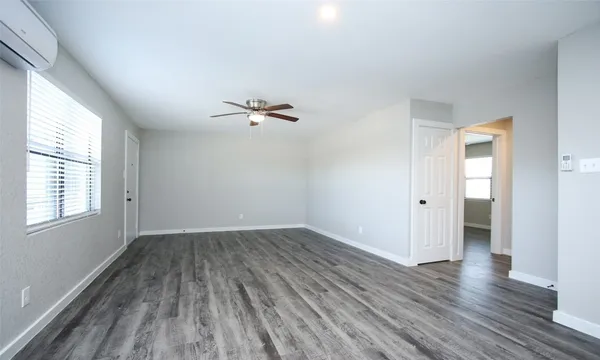 an empty room with wooden floor cabinet and windows