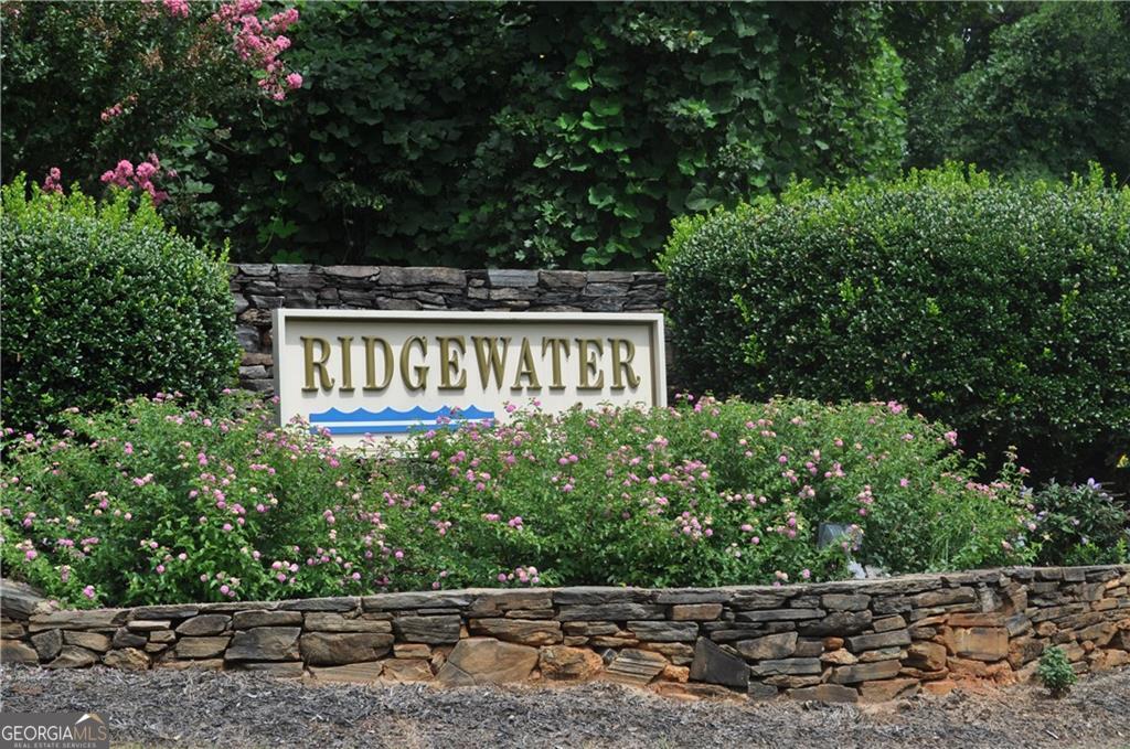 a view of a sign board with plants and trees