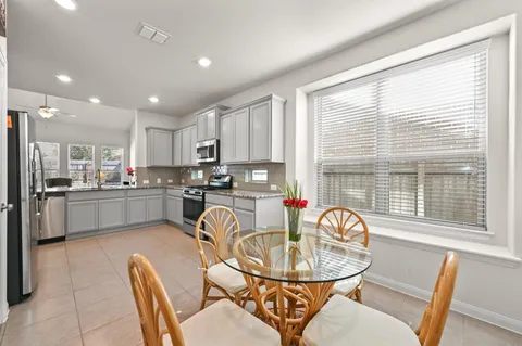 a kitchen with a dining table chairs wooden floor and stainless steel appliances