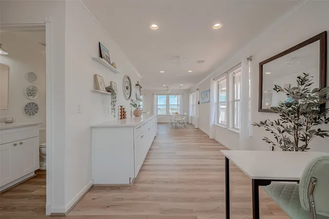 a view of an empty room with wooden floor and a kitchen