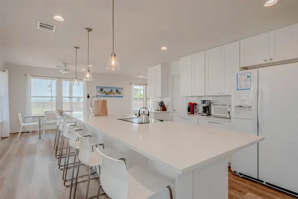 a kitchen with stainless steel appliances a white table chairs and a refrigerator