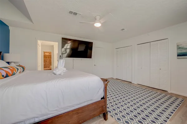 a bedroom with a bed and a flat tv screen on wall