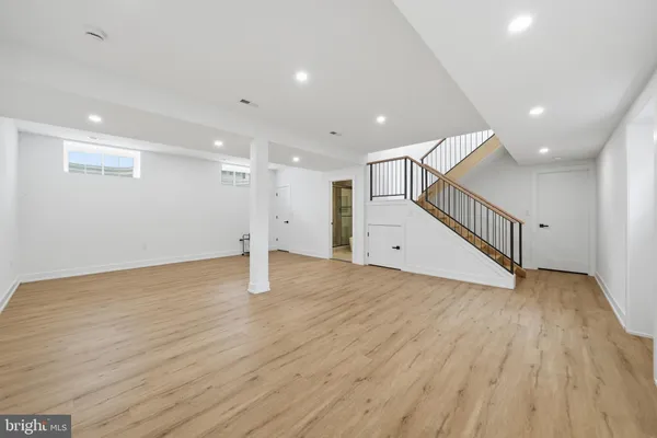 a view of a hallway with wooden floor and a bathroom