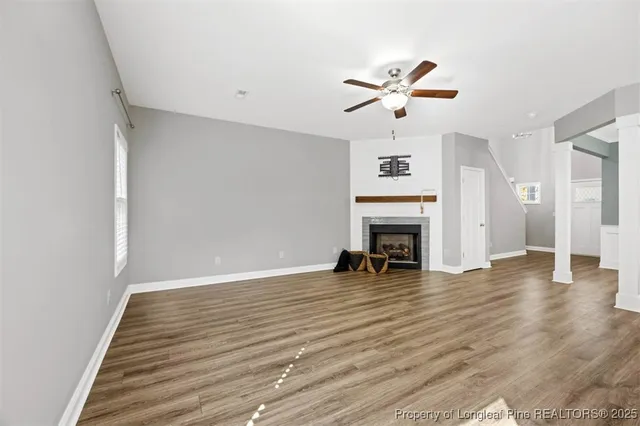 a view of an empty room with wooden floor fireplace and a window