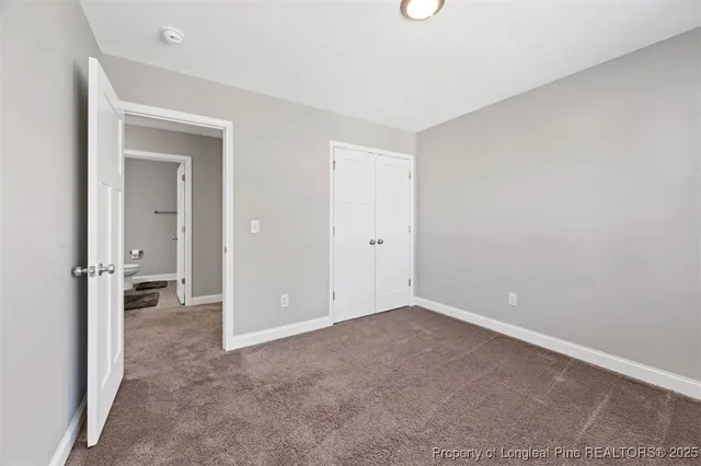 a view of an empty room with closet and a bathroom