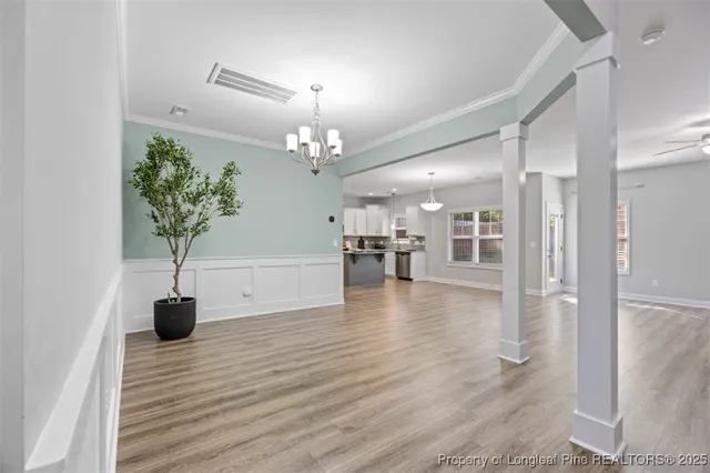a view of a hallway with wooden floor and chandelier