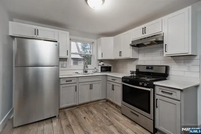 a kitchen with cabinets stainless steel appliances and wooden floor
