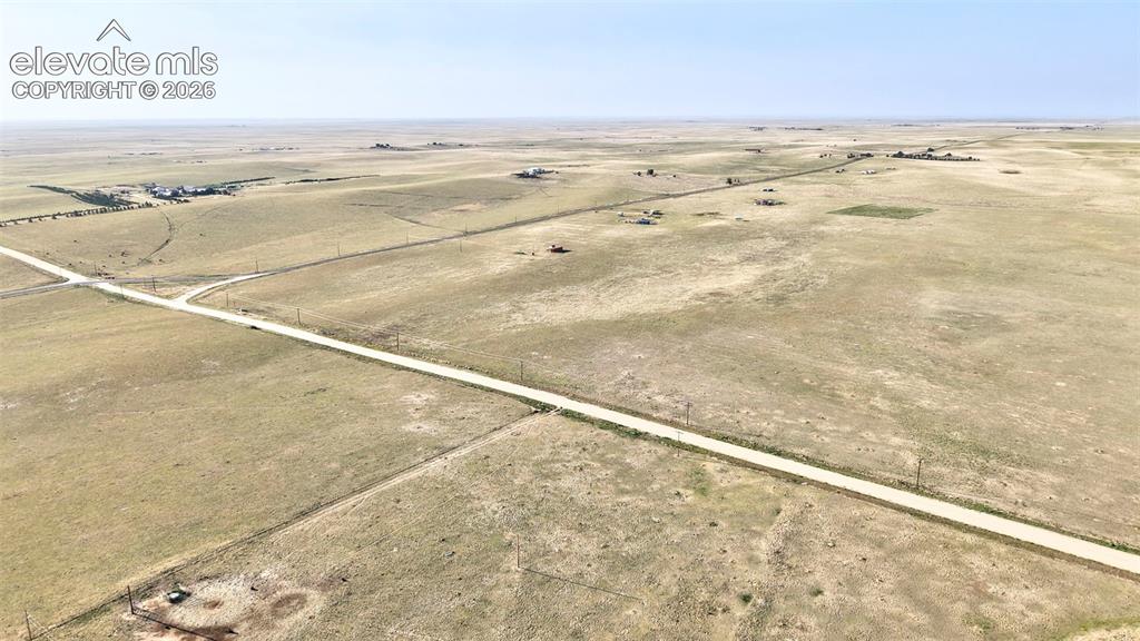 9670 Boone Road Yoder, CO 80864 - Photo 2 of 18 Expansive rural landscape featuring a long unpaved road, scattered structures, utility poles, and flat terrain