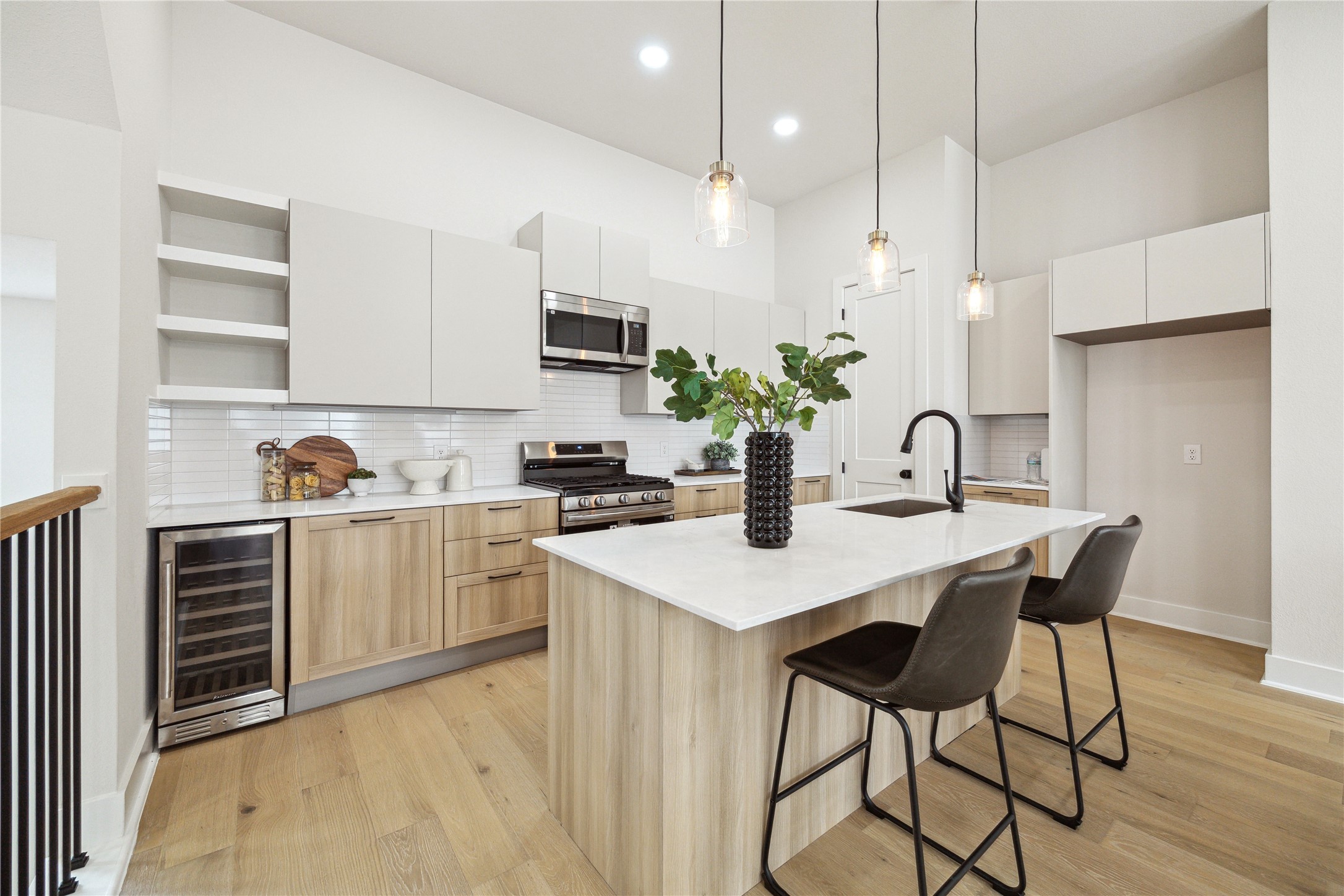 3911 Tulane Street, Unit B Houston, TX 77018 - Photo 4 of 37 Modern kitchen featuring sleek cabinetry, a spacious island with seating, stainless steel appliances, and elegant pendant lighting. Perfect for entertaining and culinary creativity.