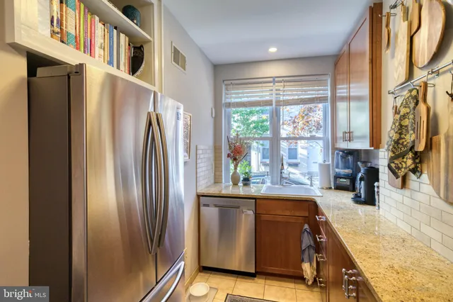 a kitchen with stainless steel appliances granite countertop a refrigerator a sink and a stove