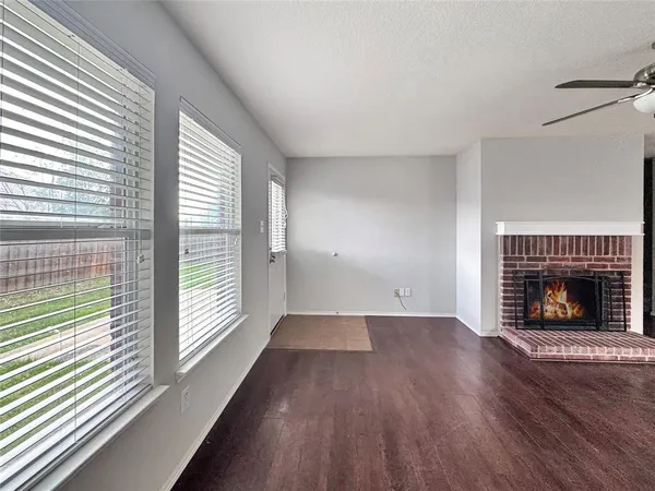 an empty room with wooden floor fireplace and windows
