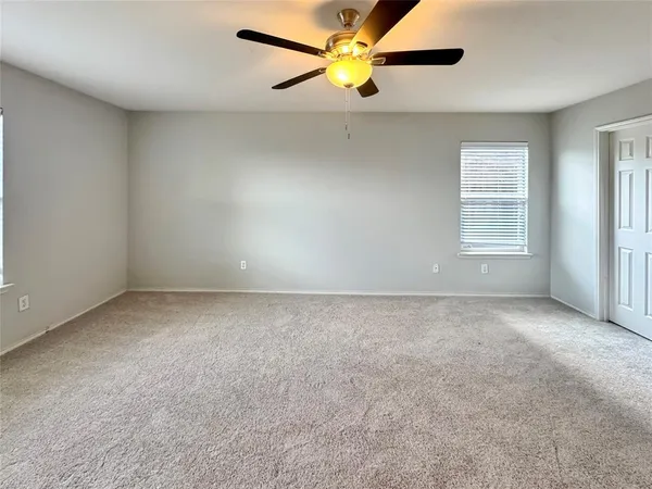 an empty room with a window and a fan
