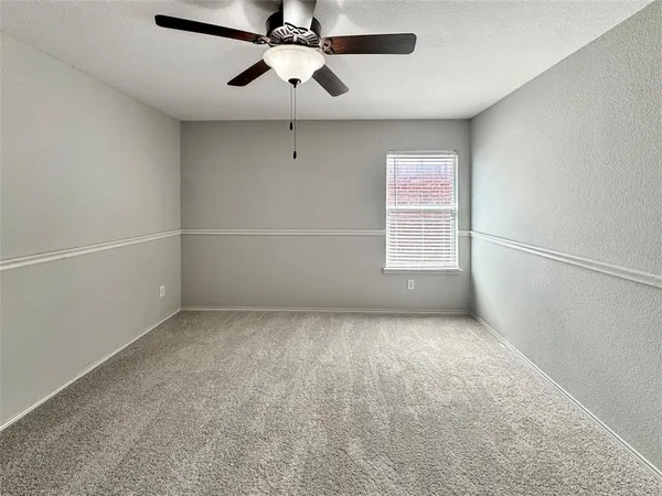 an empty room with a window and a fan