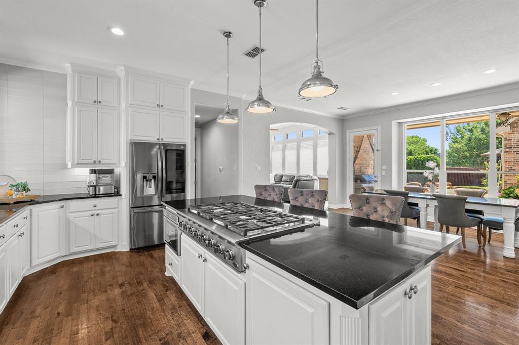 1101 Trail Ridge Drive McKinney, TX 75072 - Photo 12 of 37 a kitchen with stainless steel appliances granite countertop a stove a refrigerator a kitchen island a sink dishwasher a dining table and chairs with wooden floor