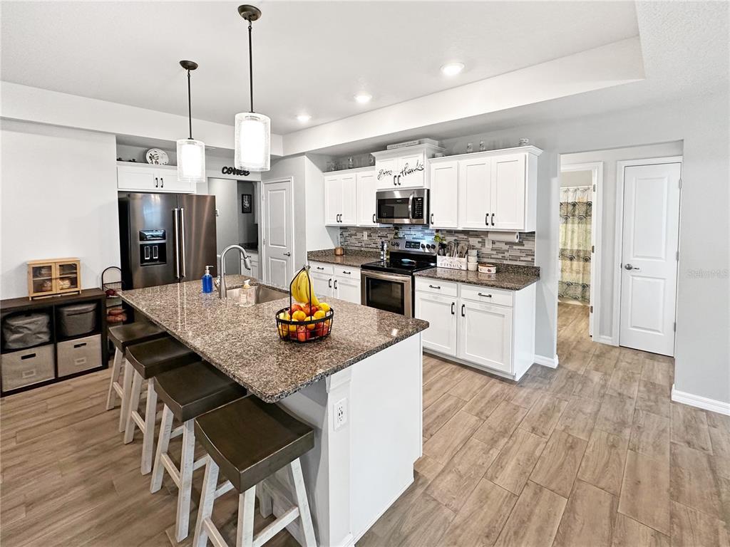 13023 Downy Woodpecker Road Weeki Wachee, FL 34614 - Photo 14 of 43 a kitchen with a stove a refrigerator and wooden floor