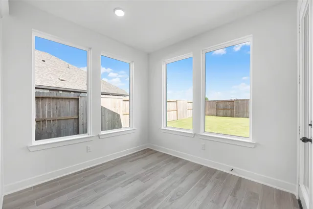 a view of an empty room with a window and wooden floor
