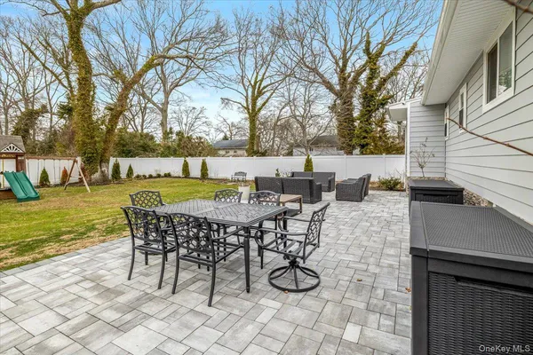 a view of a patio with table and chairs and couches with wooden floor and fence