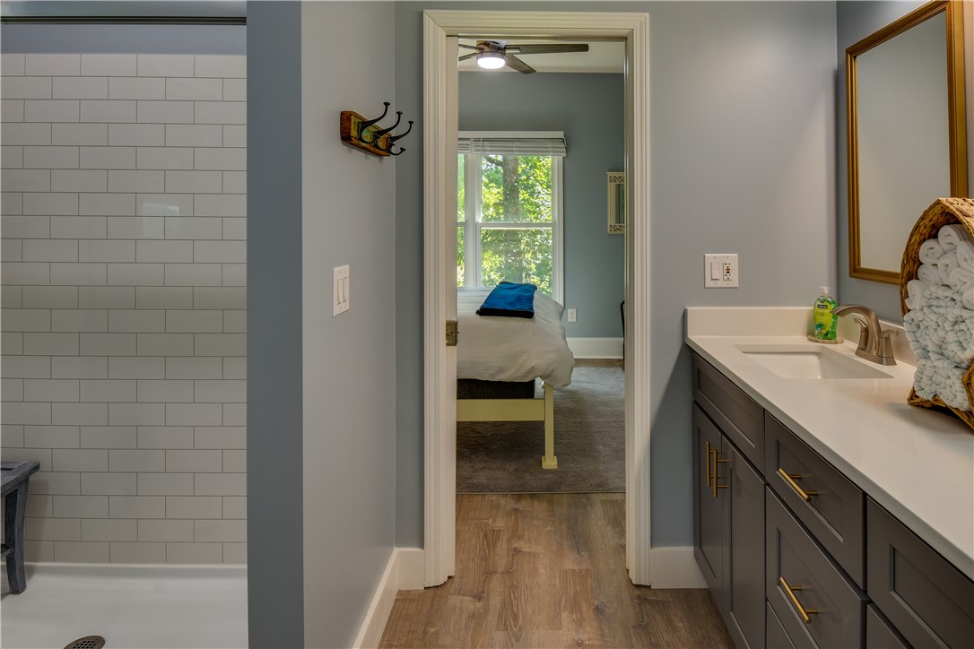 206 Petty Road Seneca, SC 29672 - Photo 22 of 48 A sleek vanity with ample counter space anchors this modern bathroom, connecting seamlessly to a bedroom through a doorway.