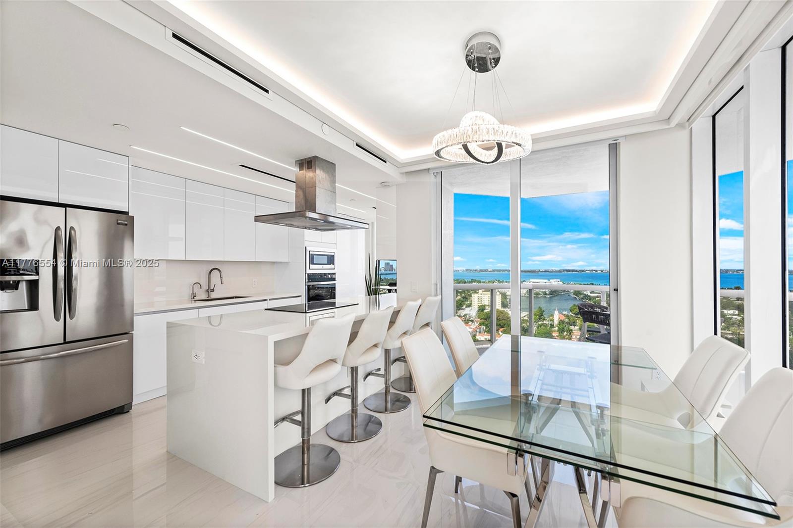 4775 Collins Avenue, Unit 2607 Miami Beach, FL 33140 - Photo 6 of 48 a kitchen with stainless steel appliances granite countertop a refrigerator a stove top oven a dining table and chairs with wooden floor