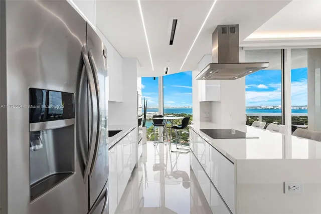 a view of a kitchen with kitchen island a large window a sink and stainless steel appliances
