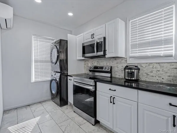 a kitchen with stainless steel appliances granite countertop white cabinets a window and a sink