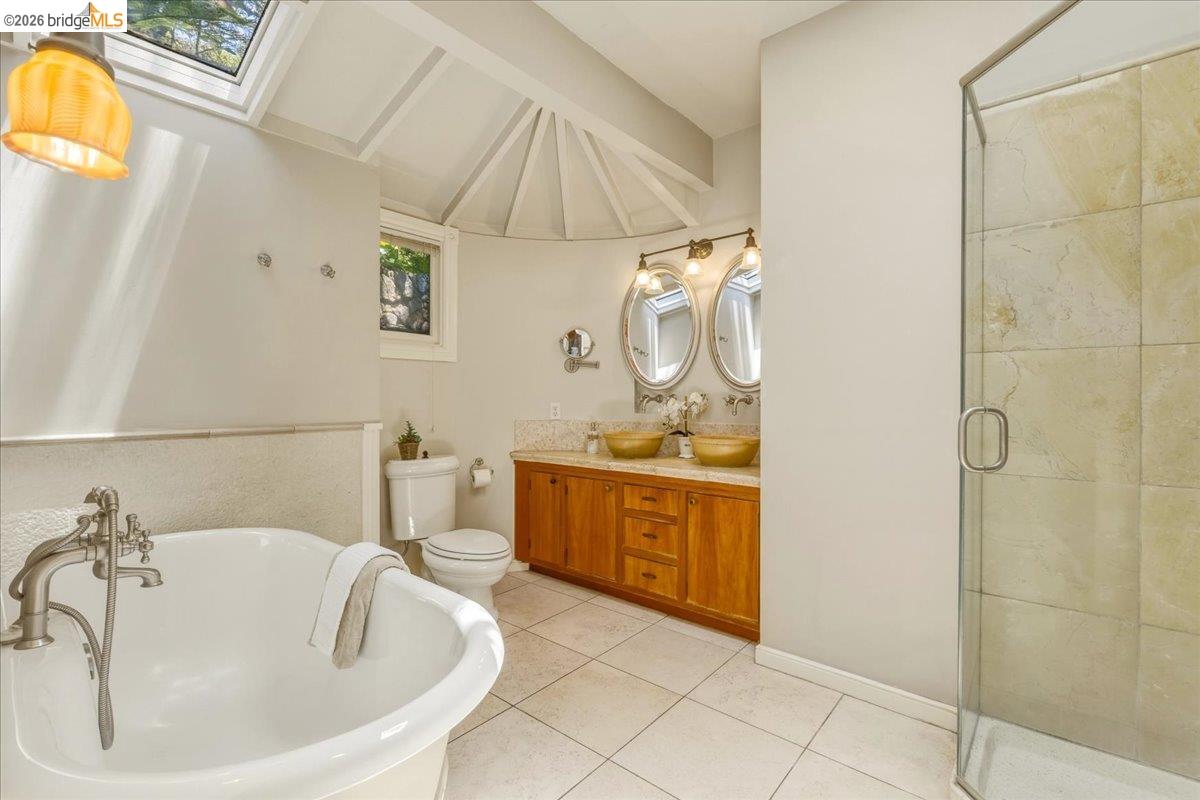 1631 La Vereda Road Berkeley, CA 94709 - Photo 23 of 42 Bathroom featuring a freestanding tub with brushed nickel fixtures, a glass-enclosed shower with tile surround, and a dual vanity with vessel sinks, wood cabinetry, and oval mirrors
