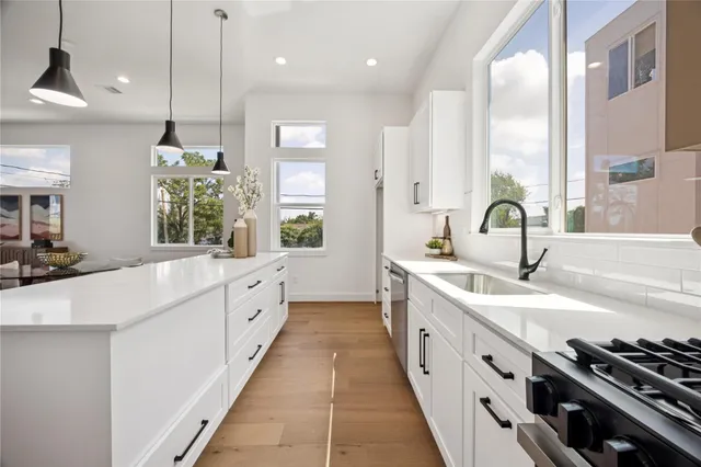 a kitchen with stainless steel appliances kitchen island granite countertop a stove a sink a dining table and chairs with wooden floor