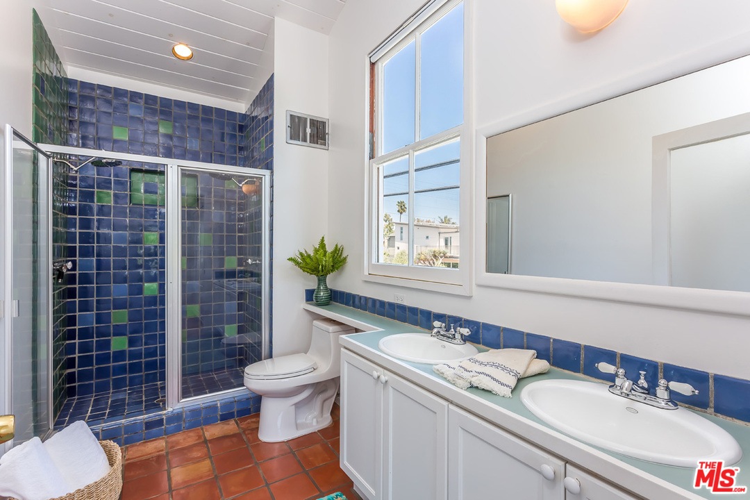 754 Marco Place Venice, CA 90291 - Photo 18 of 39 a bathroom with a granite countertop sink a toilet a mirror and shower