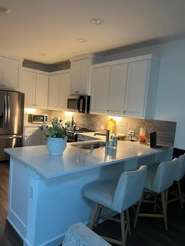 a kitchen with granite countertop a table chairs microwave and cabinets