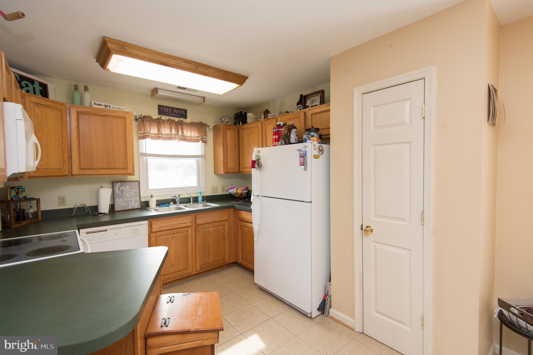 6568 Statum Road Preston, MD 21655 - Photo 9 of 49 a kitchen with stainless steel appliances granite countertop a refrigerator a sink a stove a dining table and chairs with wooden floor