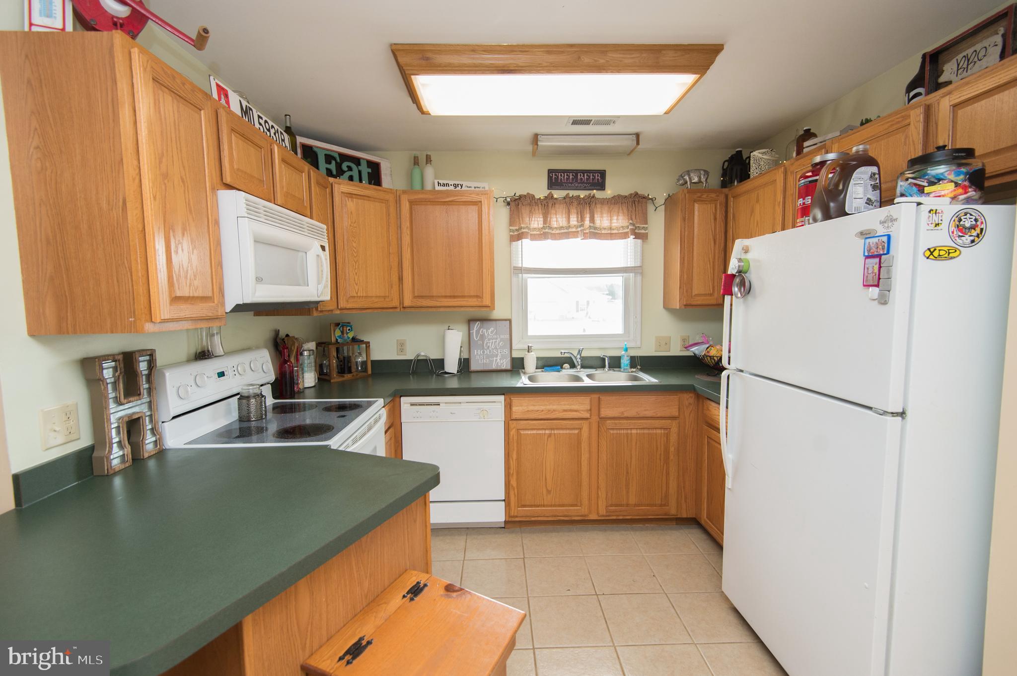 6568 Statum Road Preston, MD 21655 - Photo 10 of 49 a kitchen with a refrigerator a sink and white cabinets