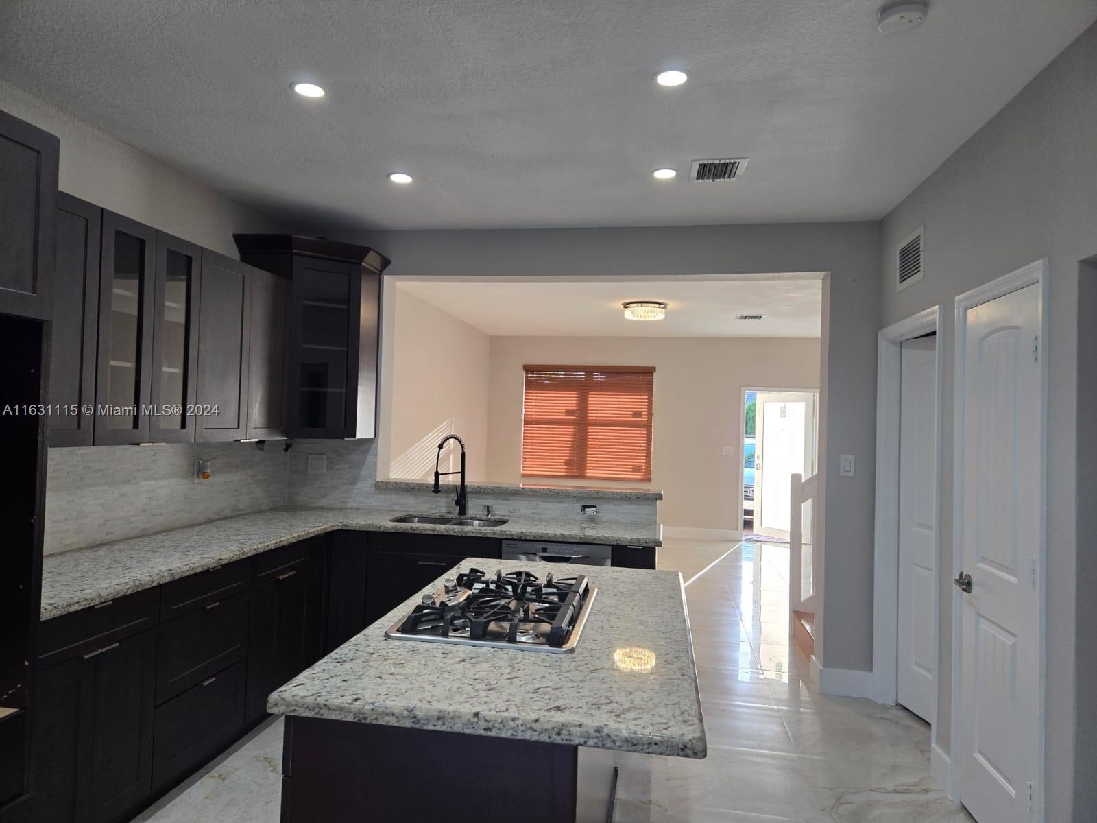 28407 Southwest 129th Place Homestead, FL 33033 - Photo 4 of 17 a kitchen with granite countertop kitchen island stainless steel appliances a sink stove and cabinets