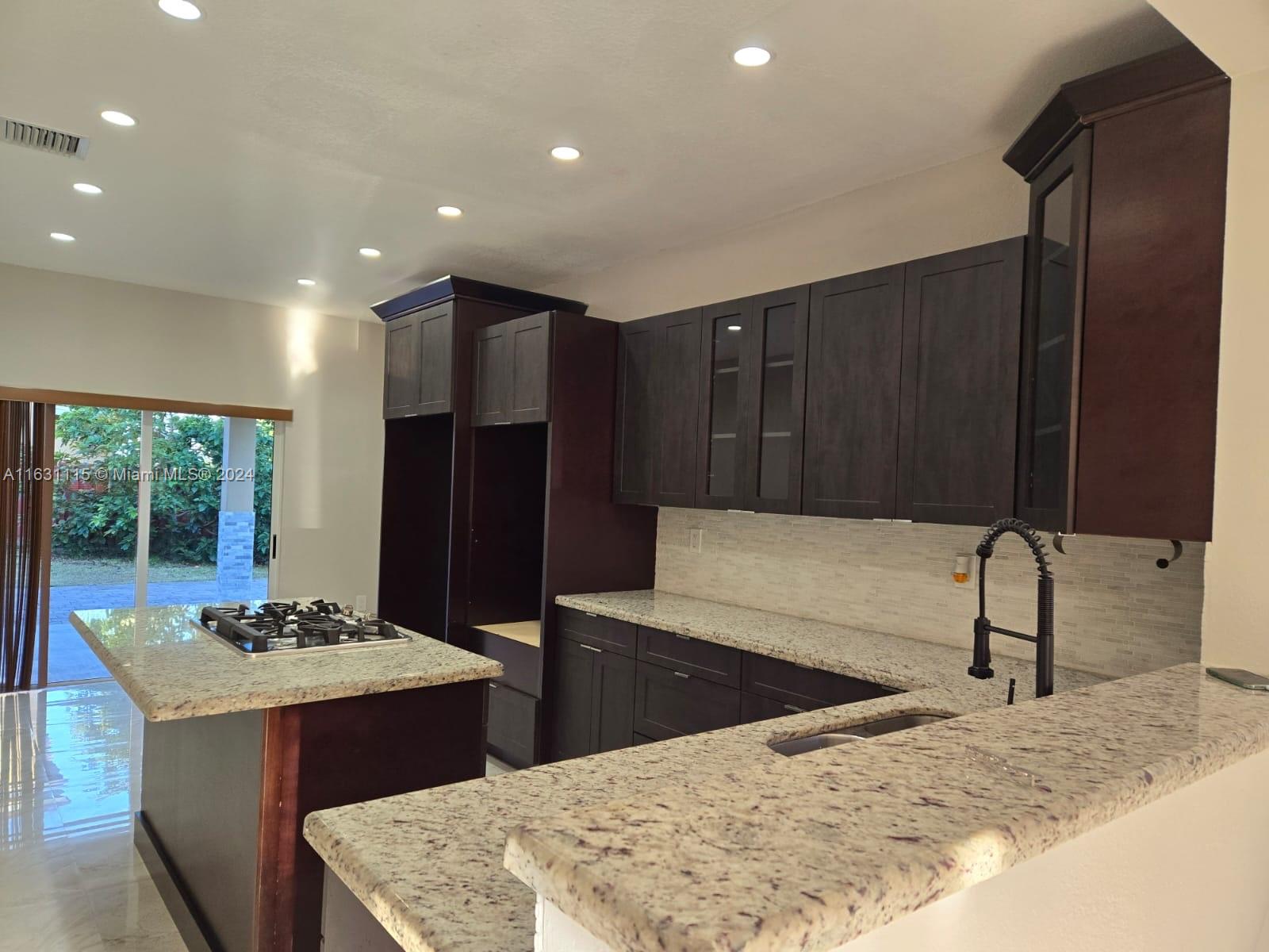 28407 Southwest 129th Place Homestead, FL 33033 - Photo 6 of 17 a kitchen with stainless steel appliances kitchen island granite countertop a refrigerator and a sink