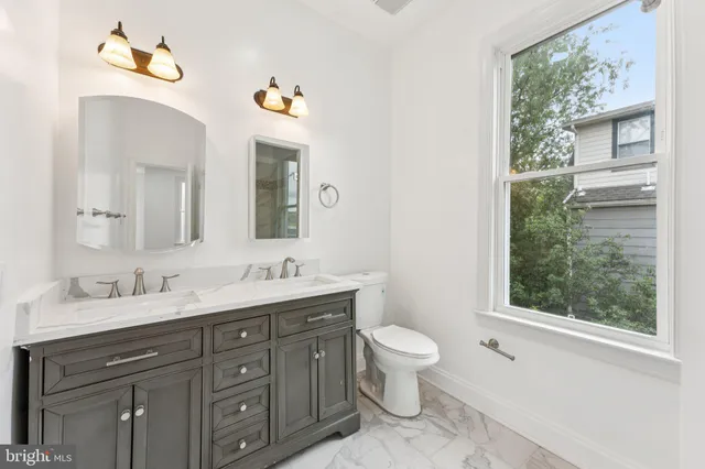 a bathroom with a granite countertop toilet sink and mirror