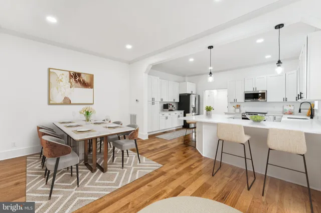 a living room with stainless steel appliances kitchen island a table chairs and a kitchen view
