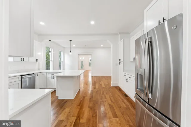 a large kitchen with kitchen island a counter top space a sink and stainless steel appliances