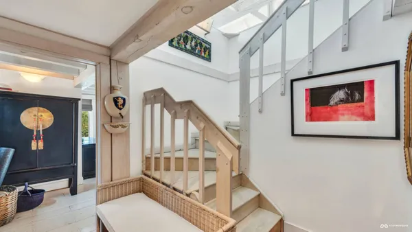 a view of staircase with lots of frames on wall and a window