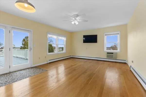 a view of an empty room with chandelier fan and wooden floor