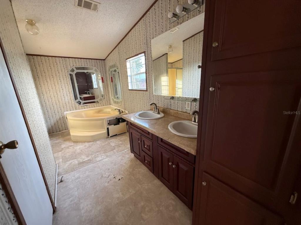 217 Longview Avenue Lady Lake, FL 32159 - Photo 6 of 10 a bathroom with a granite countertop sink a mirror and a bathtub