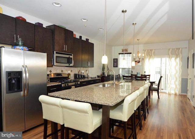 22504 Phillips Street, Unit 503 Clarksburg, MD 20871 - Photo 2 of 7 a kitchen with granite countertop a table chairs microwave and refrigerator
