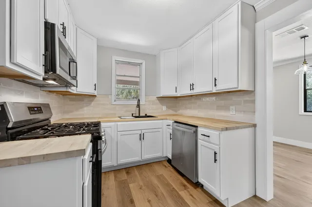 a kitchen with stainless steel appliances granite countertop a stove a sink and white cabinets